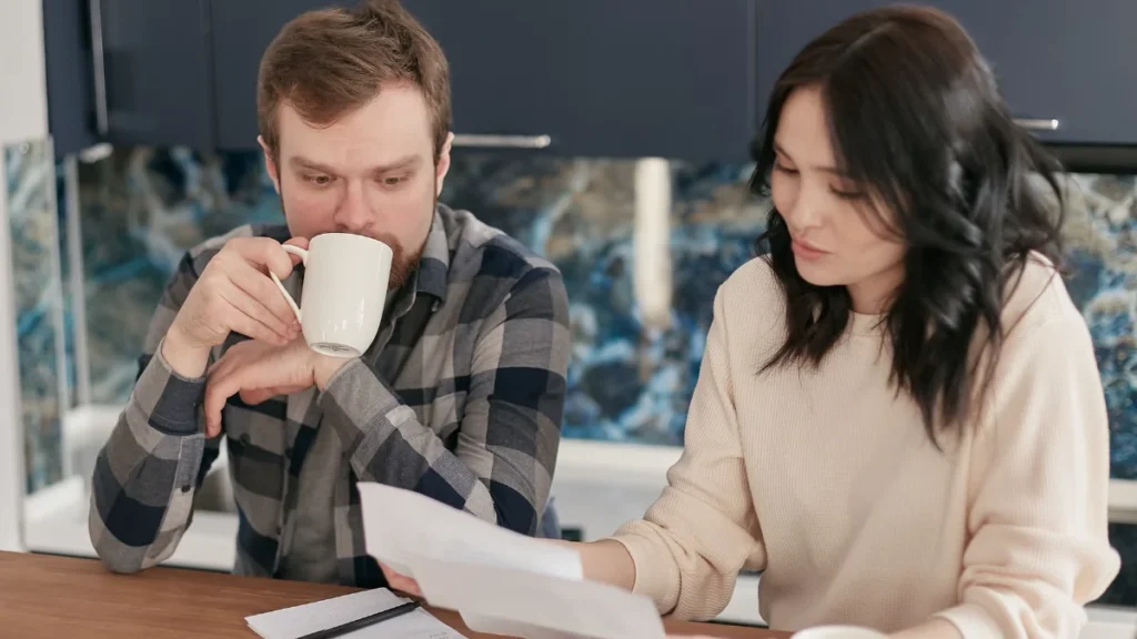 Couple reviewing bills with a calculator at the kitchen table